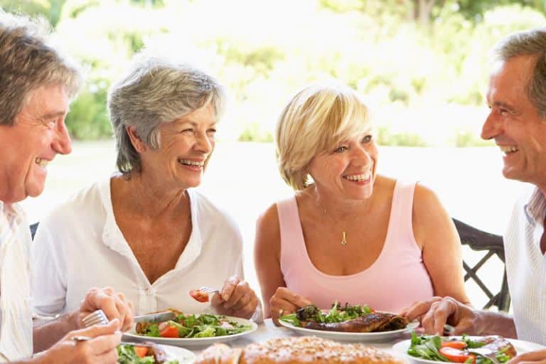 Group of retirees in retirement living having a lunch outside - lifestyle communities Australia